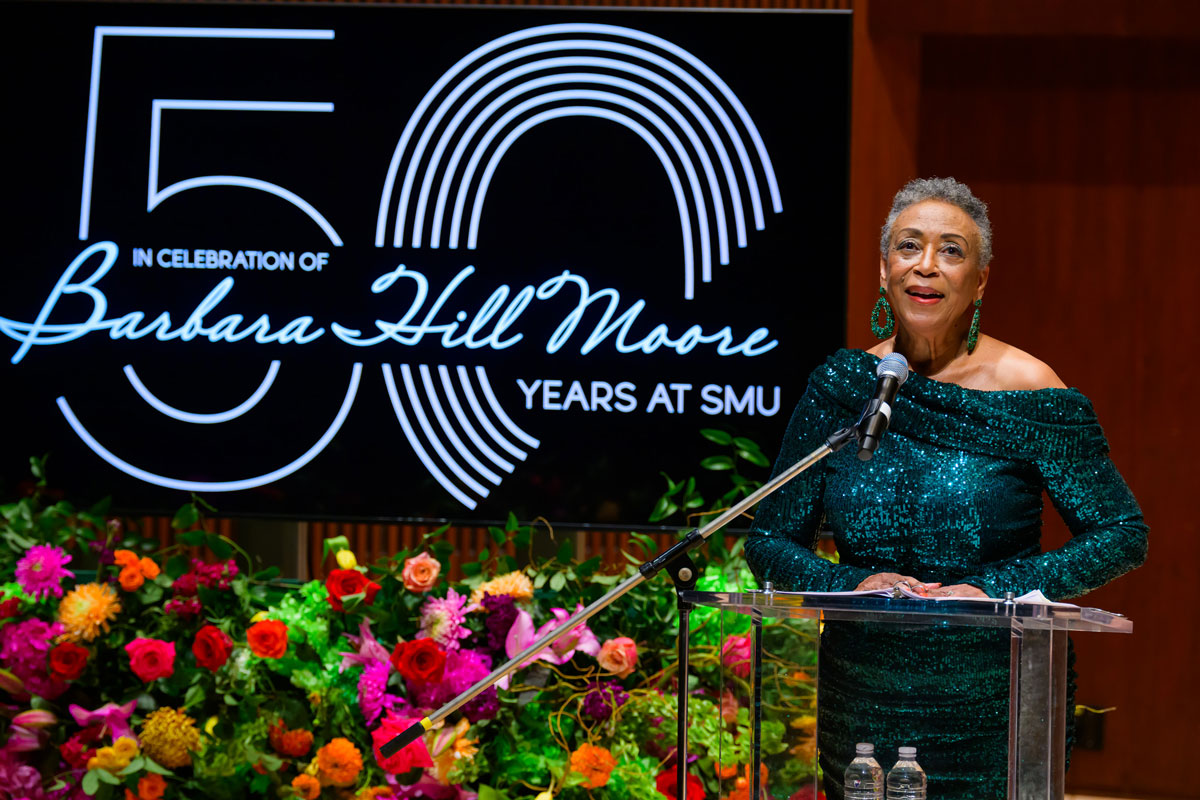 Professor Barbara Hill Moore stands at a podium at an event celebrating her 50 years at SMU.