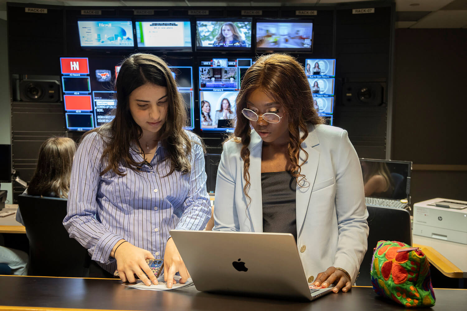two female students working at a computer in a broadcast studio
